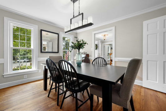 Bright dining room with a correctly proportioned chandelier centered over a white oak table, natural daylight filling the space