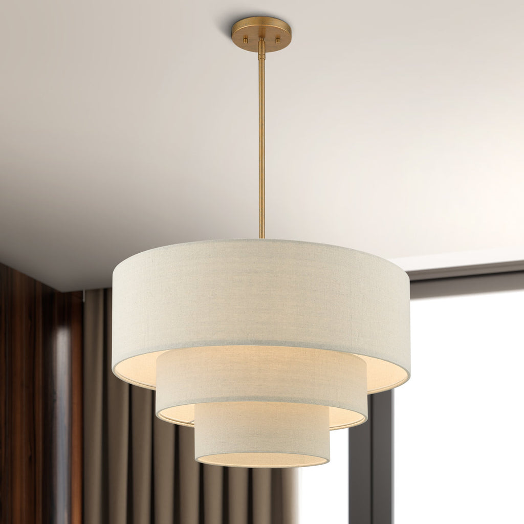 Strata 4-light tiered fabric drum chandelier with antique gold downrod and three beige drum shades