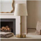 Gold cordless table lamp with slender adjustable stem and conical fabric shade
